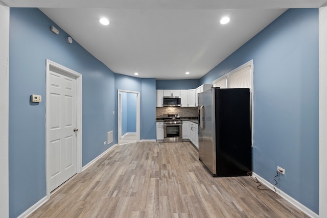 kitchen with white cabinetry, appliances with stainless steel finishes, light hardwood / wood-style floors, and backsplash