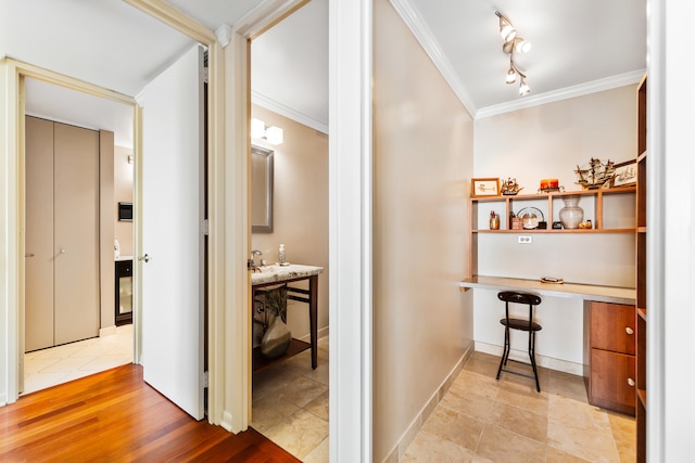 corridor with ornamental molding and light hardwood / wood-style flooring