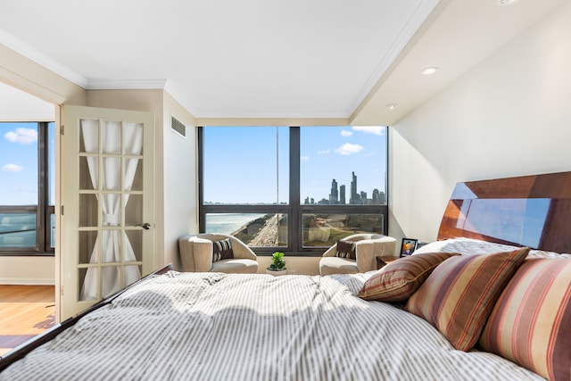 bedroom featuring a water view, hardwood / wood-style flooring, and ornamental molding