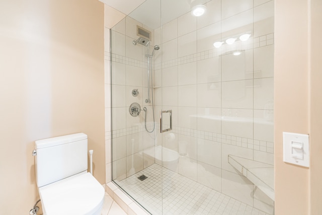 bathroom featuring toilet, tile patterned floors, and a shower with shower door