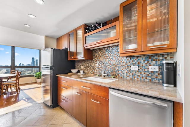 kitchen featuring light tile patterned flooring, sink, light stone counters, appliances with stainless steel finishes, and decorative backsplash