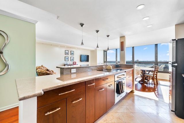 kitchen with light hardwood / wood-style floors, light stone countertops, hanging light fixtures, oven, and black electric stovetop