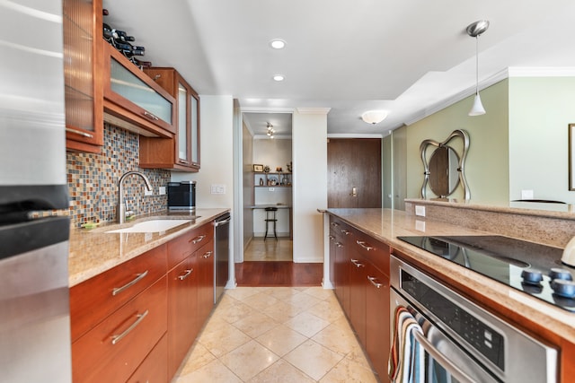 kitchen featuring light stone counters, crown molding, appliances with stainless steel finishes, hanging light fixtures, and sink