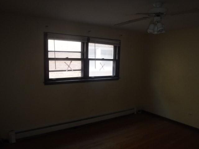 unfurnished room with a baseboard radiator, ceiling fan, and dark wood-type flooring