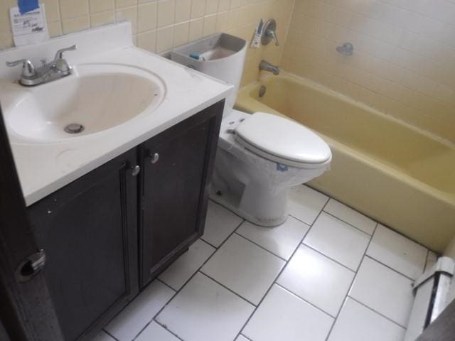 bathroom featuring tile patterned flooring, backsplash, toilet, vanity, and tile walls