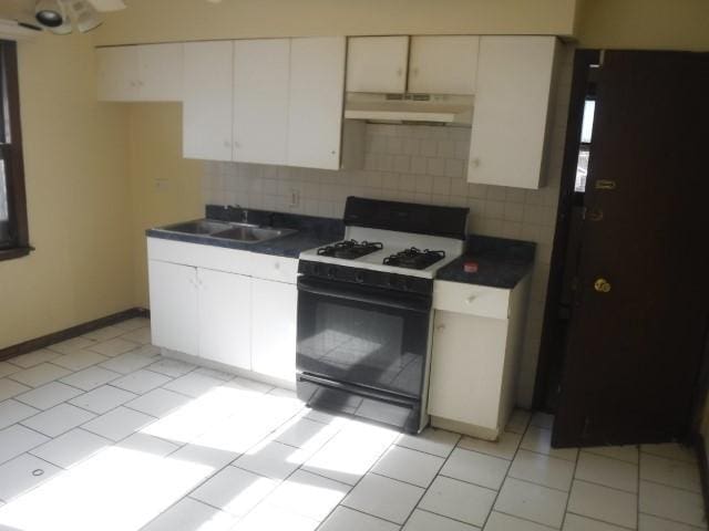 kitchen featuring decorative backsplash, white cabinets, sink, light tile patterned floors, and white range with gas stovetop