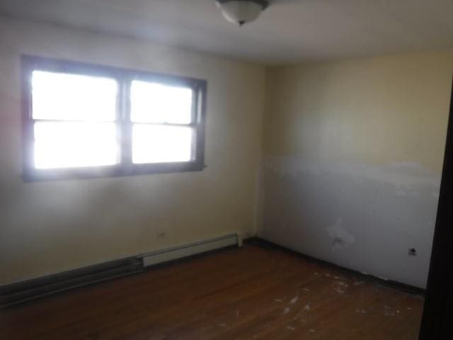 empty room with dark hardwood / wood-style floors and a baseboard heating unit