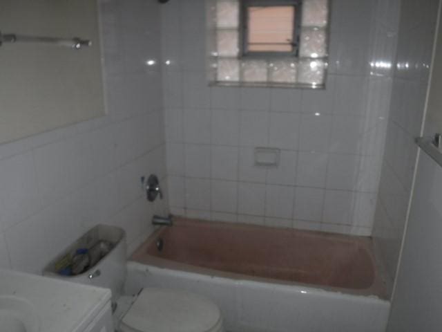 bathroom with tiled shower / bath combo and toilet