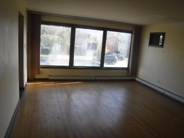 empty room with baseboard heating and dark hardwood / wood-style floors