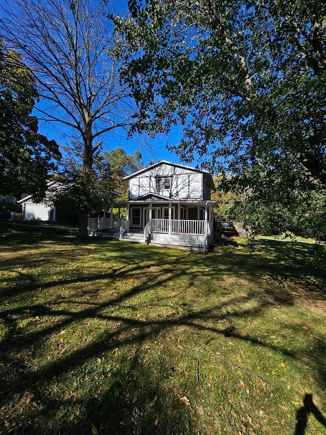 rear view of property featuring a porch and a lawn