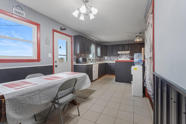 kitchen with sink, backsplash, dark brown cabinets, a kitchen island, and ceiling fan with notable chandelier