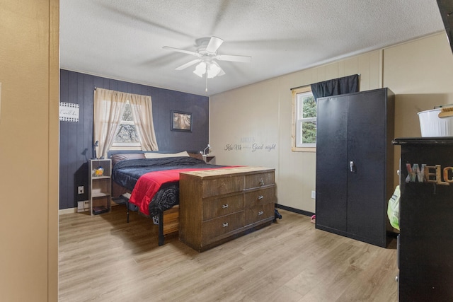 bedroom with ceiling fan, a textured ceiling, and light hardwood / wood-style flooring