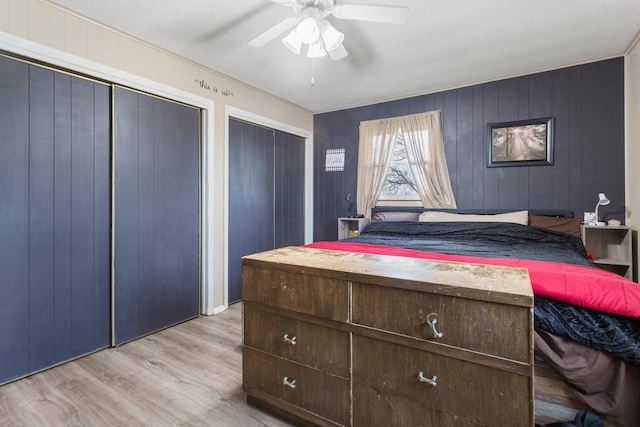 bedroom with ceiling fan, light hardwood / wood-style floors, and wood walls