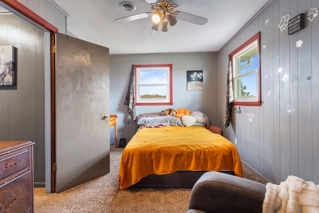 carpeted bedroom featuring a textured ceiling, ceiling fan, and wood walls