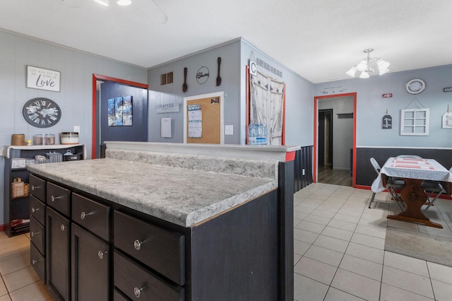 kitchen featuring a center island, light tile patterned floors, a chandelier, and ornamental molding