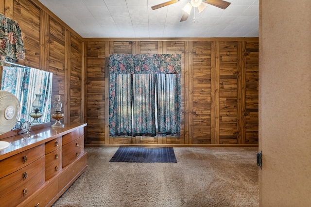 carpeted foyer featuring ceiling fan and wood walls