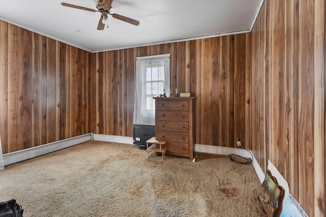 interior space with baseboard heating, ceiling fan, and wood walls