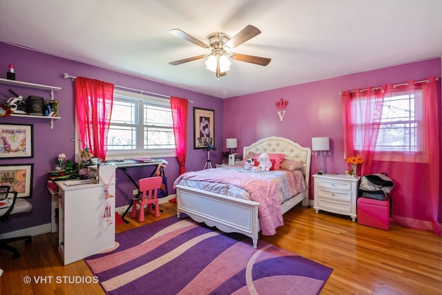 bedroom with ceiling fan, wood-type flooring, and multiple windows