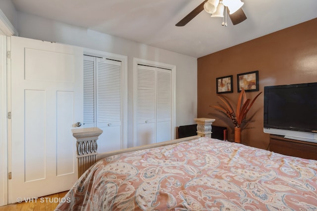 bedroom with hardwood / wood-style flooring, ceiling fan, and two closets