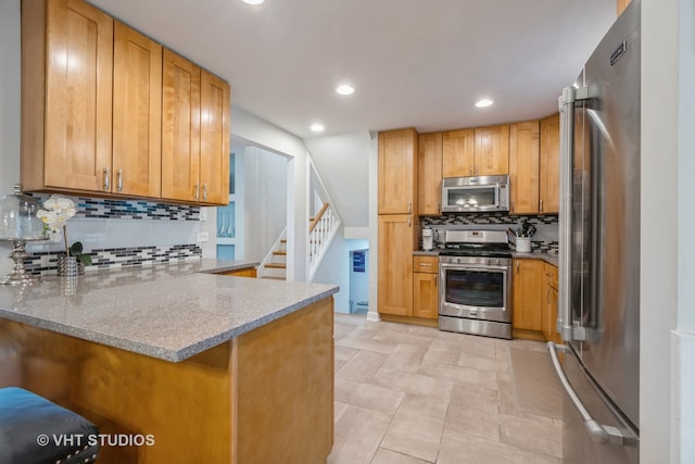 kitchen featuring tasteful backsplash, appliances with stainless steel finishes, light tile patterned floors, light stone countertops, and kitchen peninsula