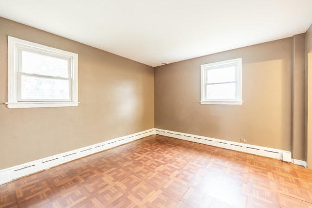 empty room featuring a baseboard radiator, a wealth of natural light, and parquet floors