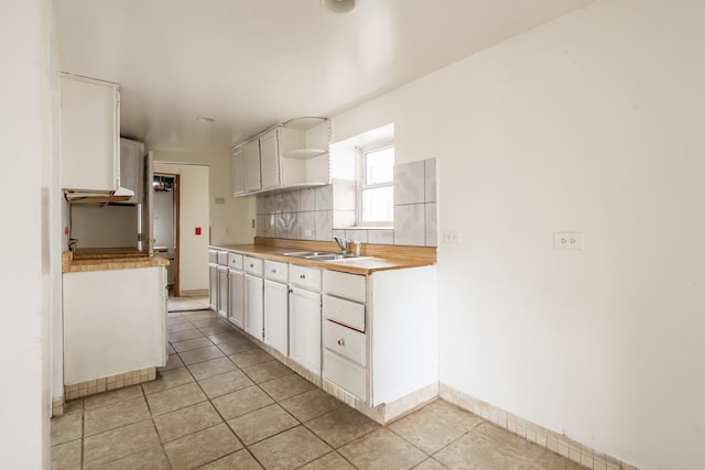 kitchen with white cabinetry, light tile patterned floors, backsplash, and sink