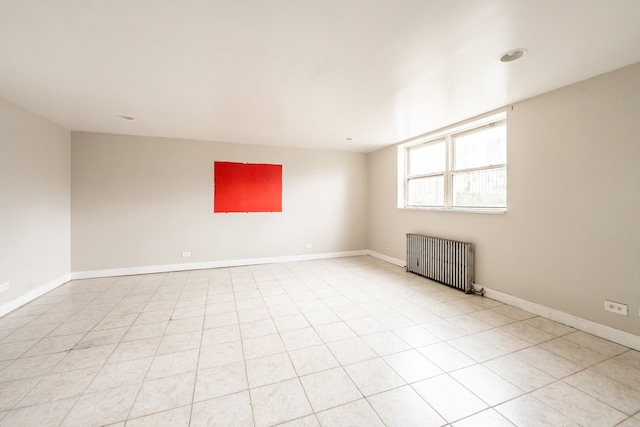 spare room featuring radiator and light tile patterned flooring