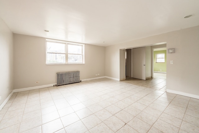 empty room featuring light tile patterned flooring and radiator heating unit