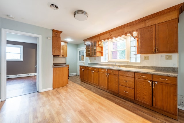 kitchen featuring tasteful backsplash, light wood-type flooring, sink, and baseboard heating