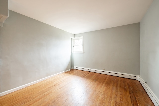 unfurnished room featuring hardwood / wood-style floors and a baseboard radiator