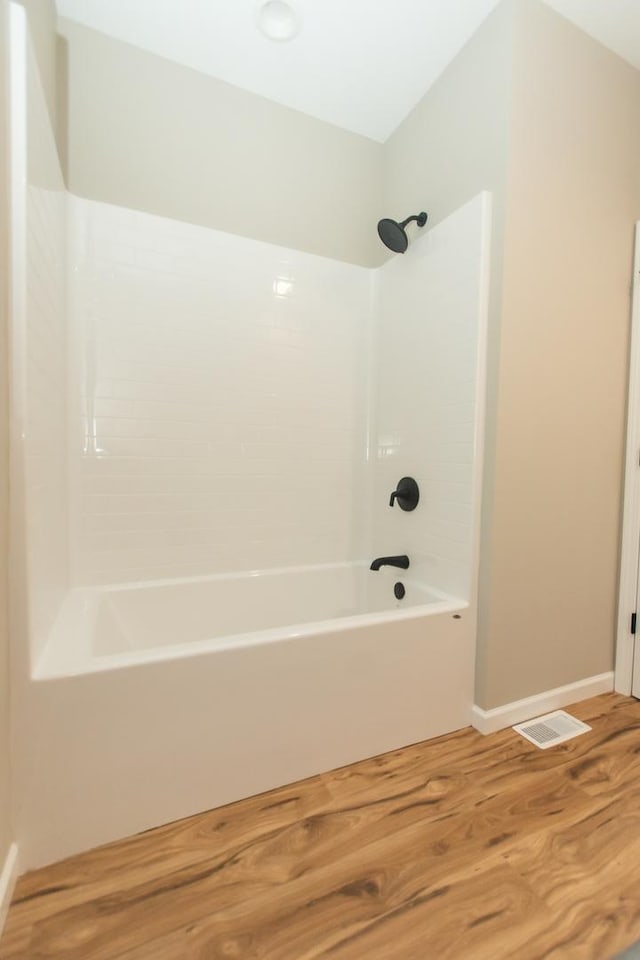 full bath featuring wood finished floors, shower / tub combination, and baseboards