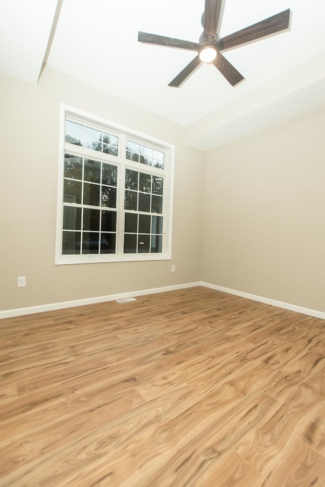 empty room with light wood finished floors, a ceiling fan, and baseboards