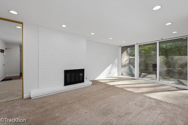 unfurnished living room with brick wall, a brick fireplace, and carpet floors