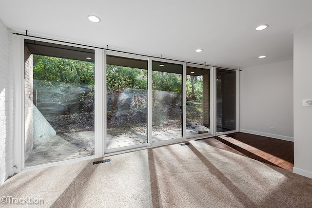 spare room featuring a wall of windows, hardwood / wood-style flooring, and plenty of natural light