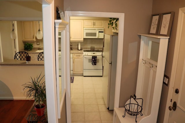 kitchen with white appliances, cream cabinetry, and light tile patterned flooring