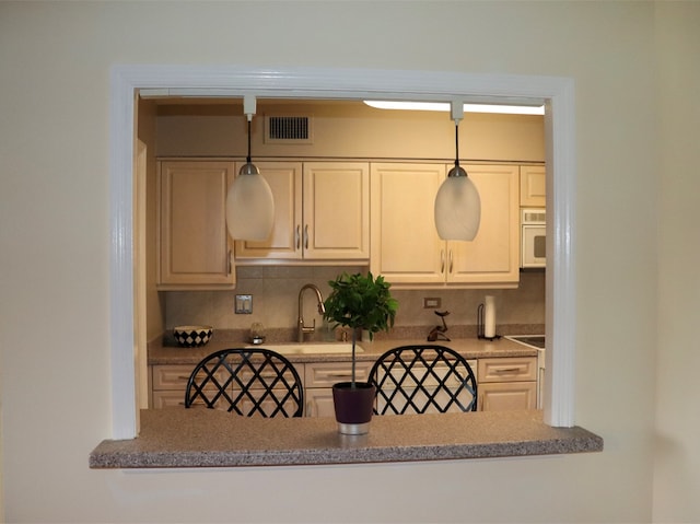 kitchen featuring backsplash, hanging light fixtures, and sink