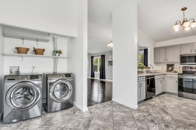 washroom with washer and dryer, light hardwood / wood-style floors, a notable chandelier, and sink