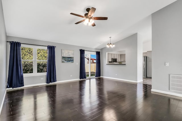 unfurnished living room featuring ceiling fan with notable chandelier, dark hardwood / wood-style flooring, and vaulted ceiling