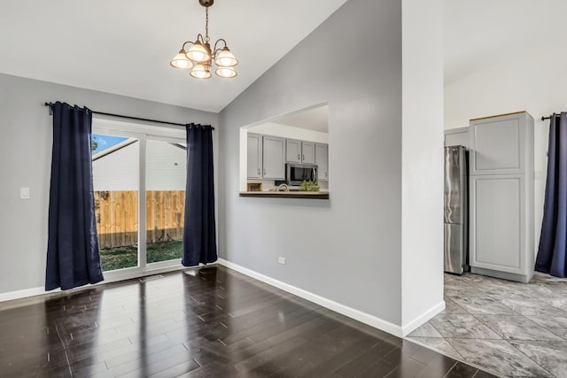 unfurnished dining area with high vaulted ceiling, hardwood / wood-style flooring, an inviting chandelier, and plenty of natural light