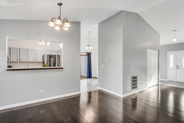 unfurnished living room with hardwood / wood-style flooring, a notable chandelier, and high vaulted ceiling