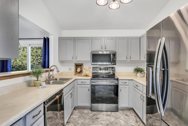 kitchen featuring lofted ceiling, sink, decorative backsplash, gray cabinets, and stainless steel appliances