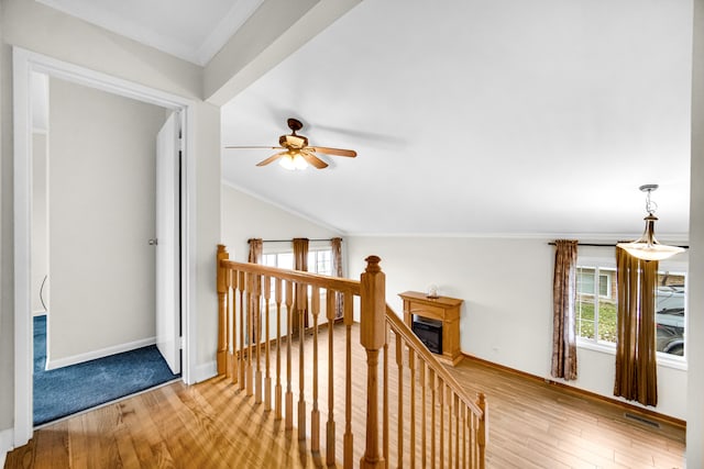 corridor with lofted ceiling, wood-type flooring, and ornamental molding