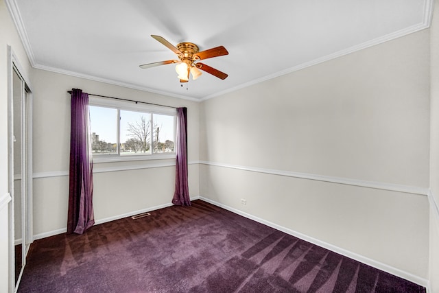 empty room featuring ceiling fan, crown molding, and dark carpet