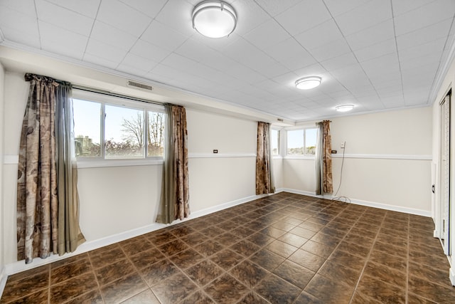 tiled empty room featuring a healthy amount of sunlight and crown molding