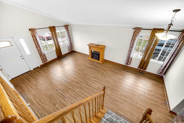 entrance foyer with lofted ceiling, hardwood / wood-style flooring, crown molding, and plenty of natural light