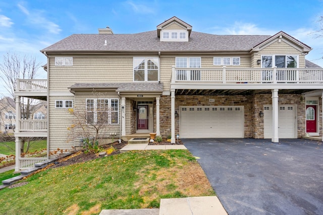 multi unit property featuring a garage, a balcony, and a front lawn