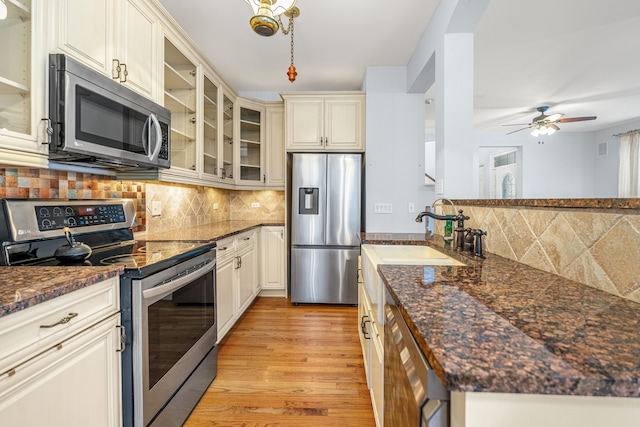 kitchen featuring appliances with stainless steel finishes, light wood-type flooring, backsplash, ceiling fan, and sink