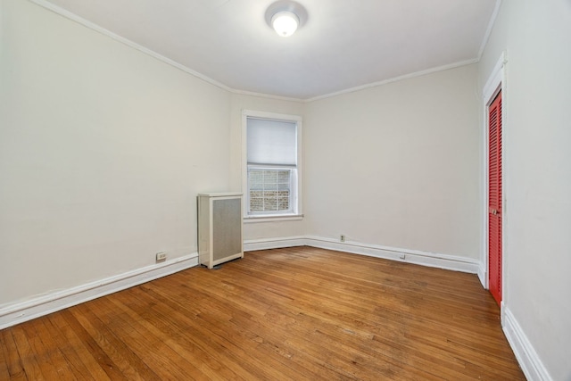 empty room with ornamental molding, hardwood / wood-style floors, and radiator heating unit