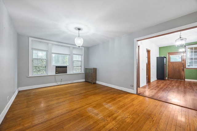 empty room featuring an inviting chandelier and hardwood / wood-style floors