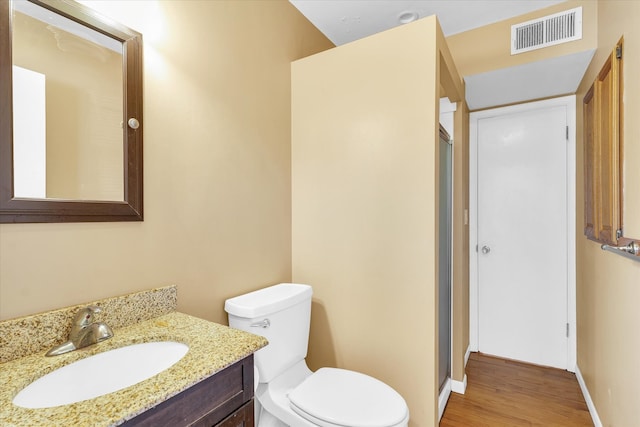 bathroom with toilet, vanity, and wood-type flooring